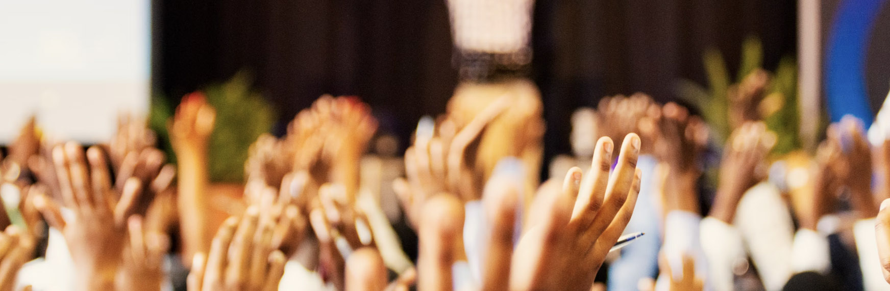 Hands raised at a keynote event
